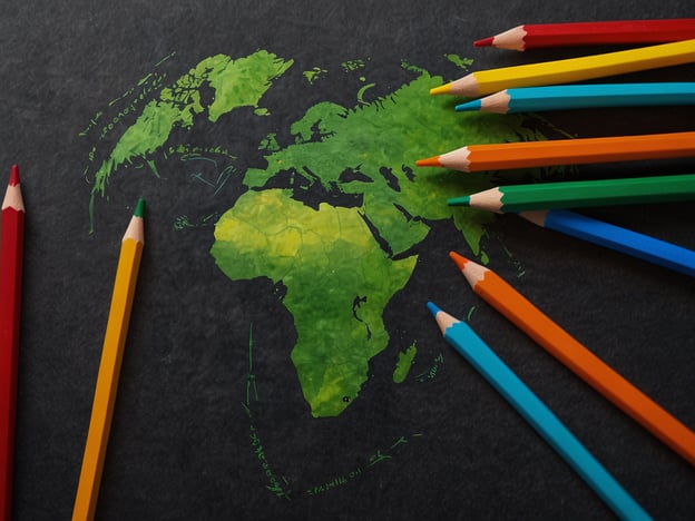 Auf dem Bild ist eine stilisierte Karte von Afrika zu sehen, die in verschiedenen Grüntönen dargestellt ist. Um die Karte sind Buntstifte in verschiedenen Farben angeordnet. Diese Darstellung könnte symbolisch für die zukünftige Entwicklung Ruandas stehen, besonders im Hinblick auf Umweltfragen und Bildung. Ruanda hat sich in den letzten Jahren stark auf nachhaltige Entwicklung und den Schutz der Umwelt konzentriert. Die Verwendung von Farben könnte den kreativen Ansatz und die Bedeutung von Bildung in diesem Prozess unterstreichen.