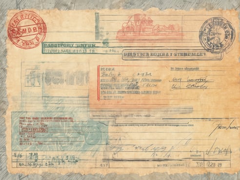 Ein altes, vergilbtes Dokument, das auszusehen scheint wie ein Reisepass oder eine ähnliche Passkontrolle. Das Dokument enthält Stempel in verschiedenen Farben, handschriftliche Notizen und Nummerierungen. Es sind auch mehrere Textfelder sichtbar, die internationale Informationen und möglicherweise Personalangaben enthalten. Der Zustand des Papiers zeigt Spuren der Abnutzung und Alterung, mit sichtbaren Falten und Verfärbungen.