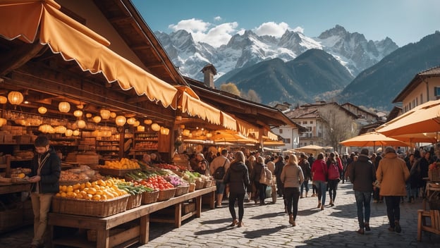 Markt mit bunten Ständen, frischen Früchten und Gemüse, viele Menschen bummeln vor den Alpenkulissen.