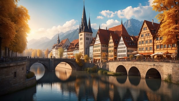 Historische Altstadt mit bunten Häusern, einer Brücke und Bergen im Hintergrund, umgeben von herbstlichen Bäumen.